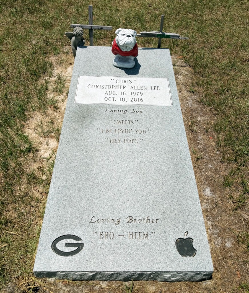 Chris Lee's grave stone embossed with UGA's G logo and the Apple Computer apple with a bite taken out logo.