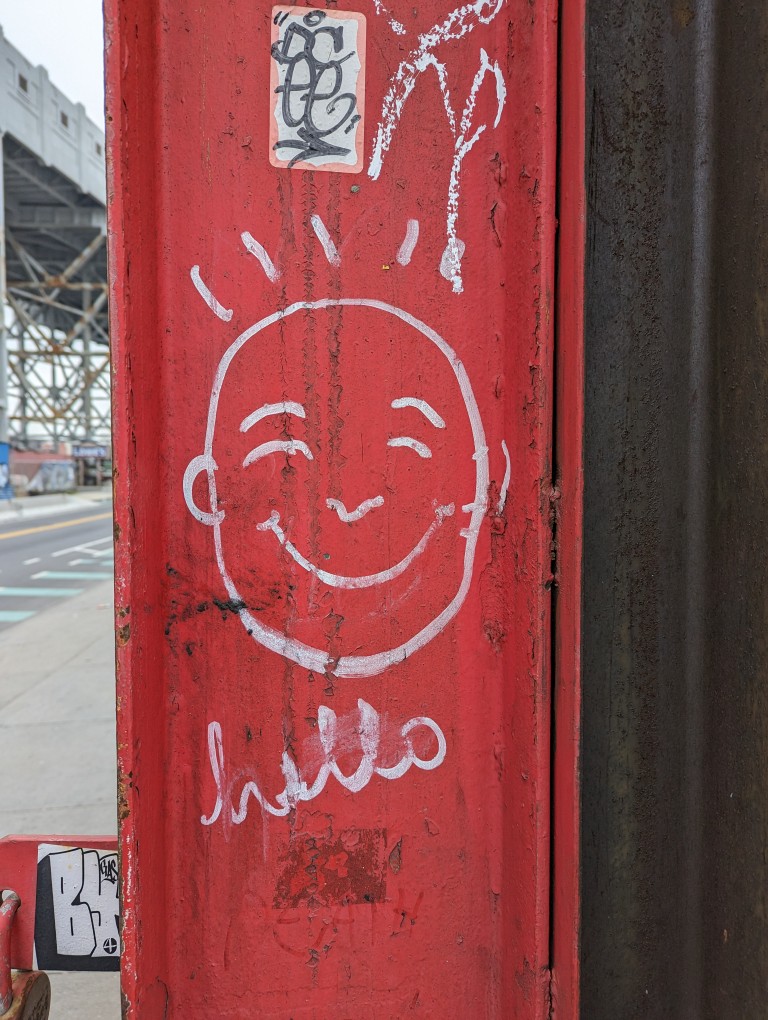 Drawing of a smiling face above the cursive word, "hello" on a vertical steel I-beam